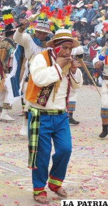 ZAMPOÑEROS: El varón en esta danza representa al hombre del altiplano que siembra y cosecha la tierra, expresa su alegría con las melodías de las zampoñas para pedir a la naturaleza la presencia de lluvias frente a las sequías y así tener una buena cosecha.
El traje que viste este personaje es el siguiente: tiene un sombrero hecho de lana de oveja de color blanco lleva dos plumas de colores dispuestas en la parte superior de la copa del sombrero, además lleva dos ch’uspas tejidas con lana de diferentes colores colgadas en el cuello y cruzadas en el pecho.
Tiene una camisa blanca o negra de cuello cadete con mangas largas, además de un chaleco con detalles de aguayo. También lleva una faja o chumpi puesta de manera ajustada en la cintura.
El pantalón es confeccionado de tela de bayeta de la tierra, el color difiere de un grupo a otro e incluso de bloque a bloque, este es de color negro, a veces chillón, en algunos casos tienen adornos en el botapié, algunos llevan medias de caytu de color blanco y otros sólo las abarcas de cuero de res o de goma. Además lleva una zampoña la cual es interpretada en todo el recorrido.