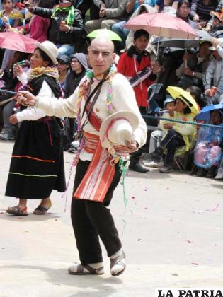 DANZANTE VARÓN: Es el hombre del altiplano boliviano, parte importante en la economía familiar, trabaja junto a su familia y la comunidad, en la siembra y la cosecha de la tierra, actividad fundamental para la subsistencia de los pueblos.
El danzante lleva en algunos casos un lluch’u o gorro con orejas tejido con lana de oveja, sin decoración, una camisa o kawa de bayeta con un escote en V, un aguayo de colores en el que lleva algunas de sus pertenencias, además de la wist’alla que es una bolsa grande hecha de tejido multicolor en la que lleva coca y va cruzada sobre el hombro.
Asimismo, lleva la ch’uspa o bolsa de tejido que va colgada al cuello en la que también lleva coca y un poco de alcohol en una botella pequeña, en su mano lleva una khorawa más conocida como honda, hecha de material flexible, usualmente de cuero, que utiliza para lanzar piedras.
En su cintura lleva una wak’a o faja ancha elaborada con tela de aguayo de colores vistosos además de la ch’uspa o bolsita que va colgada a la cintura para sujetar el pantalón, confeccionado en bayeta de tierra, medias de caytu y wikhus o abarcas de cuero o goma de color negro.