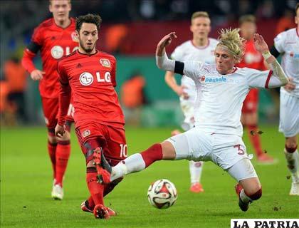 El jugador del Bayer Leverkusen, Hakan Calhanoglu disputa el balón con Tim Heubach