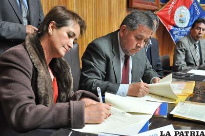 Rosario Mendizábal representante de la Procuraduría y Carlos Antezana rector de la UTO firman el convenio