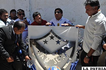 Gerson Cuaquira hace la entrega de un escudo del club San José, reciben el obsequió Edwin Zeballos y Marcos Ferrufino