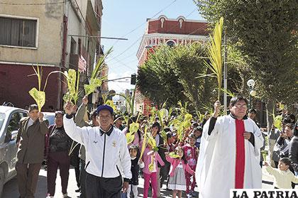 La población bate las palmas en la procesión del Domingo de Ramos