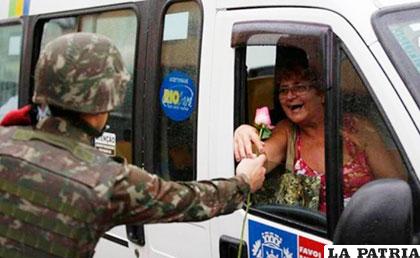 Un soldado del ejército brasileño entrega una flor por el Día Internacional de la Mujer