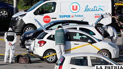 Un policía forense investiga un carro del supermercado de la cadena 