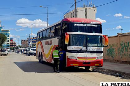 Un efectivo del orden conmina a abandonar el lugar al conductor de un vehículo de la empresa Buses El Alto