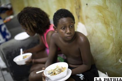 Un niño tiene un plato de comida donada por grupos de ayuda dentro de un edificio ocupado, en medio de la pandemia de coronavirus, en Río de Janeiro /AP Foto/Silvia Izquierdo