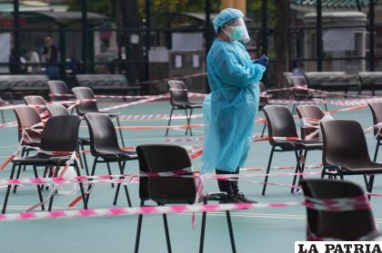 Una trabajadora sanitaria, vestida con un equipo de protección, espera la llegada de residentes para someterse a pruebas de detección del coronavirus 
/AP Foto /Vincent Yu
