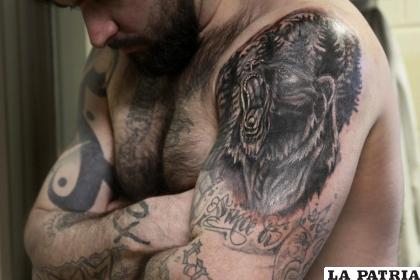 Erik Eck muestra el tatuaje de un oso que reemplazó al de un león, que lo identificaba como miembro de la pandilla Latin Kings 
/DuPage County Sheriff’s Office vía AP
