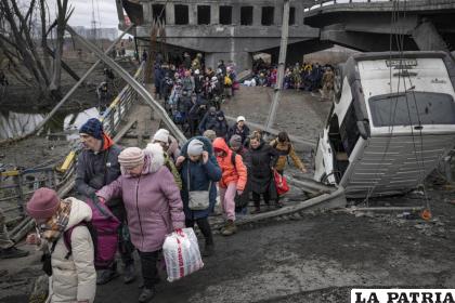 Numerosas personas transitan por un camino improvisado bajo un puente destruido durante un ataque aéreo ruso /AP Foto /Vadim Ghirda
