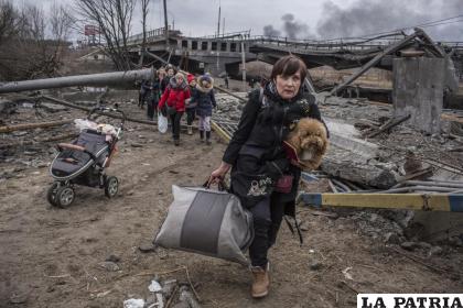 Gente cruza por una ruta improvisada bajo un puente destruido en la localidad de Irpin, Ucrania / AP Foto /Oleksandr Ratushniak