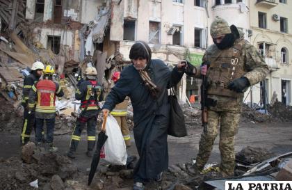 Un voluntario de las Fuerzas Ucranianas de Defensa Territorial ayuda a una mujer a cruzar la calle en Járkiv, Ucrania /AP Foto/Andrew Marienko
