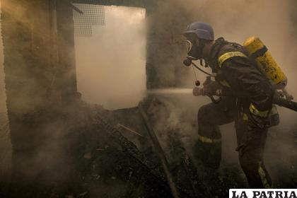 Un bombero ucraniano rocía agua en una casa destruida por proyectiles en Kiev 
/AP Foto /Vadim Ghirda