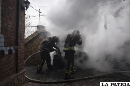 Bomberos extinguen un auto incendiado que fue bombardeado por fuerzas rusas /AP Foto /Evgeniy Maloletka