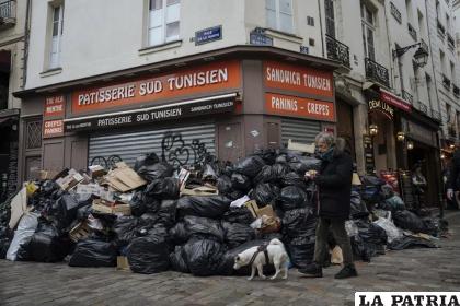 Un hombre pasa caminando junto a montones de basura en París /AP Foto/Lewis Joly