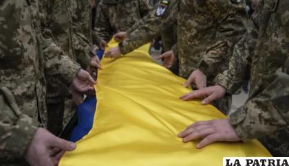 Militares ucranianos doblan la bandera nacional sobre el ataúd de su camarada Andrii Neshodovskiy durante la ceremonia fúnebre en Kiev, Ucrania /AP