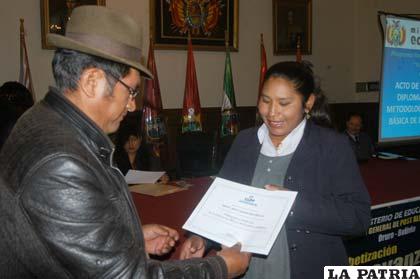 El secretario de Desarrollo Social de la Gobernación entrega el certificado del diplomado a una maestra
