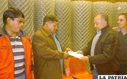 El gerente de Corinsa, Omar Eid, entrega la donación de la malla olímpica al ejecutivo de los fabriles Rubén Cejas.