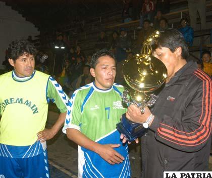El capitán de Coremmin, Juan Rocha, recibe el premio de campeón de manos del dirigente Edgar Martínez.