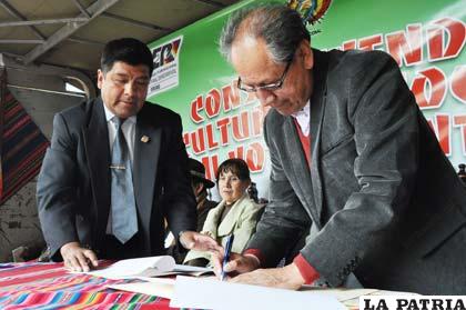El presidente del TEDO, Benjamín Moya, firma el documento junto al representante de Save the Children