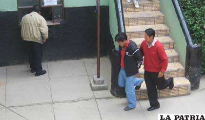 Uno de los sospechosos es llevado por un funcionario de la Felcc