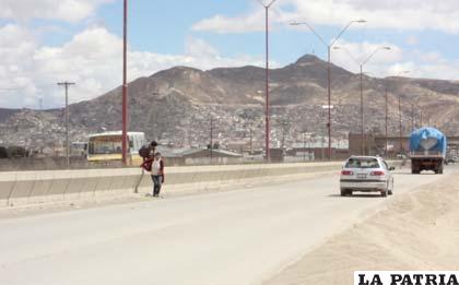 Arriesgando su vida, los peatones cruzan la avenida saltando la jardinera central