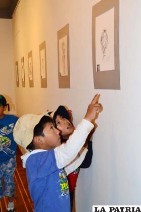 Niños observan las obras de sus compañeros en el ISBA
