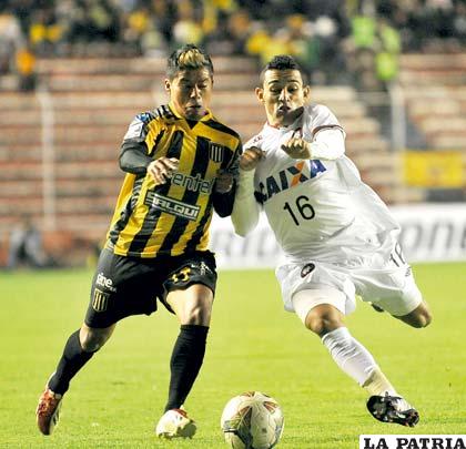 Nelvin Soliz que fue la figura del partido, disputa el balón con Natanael