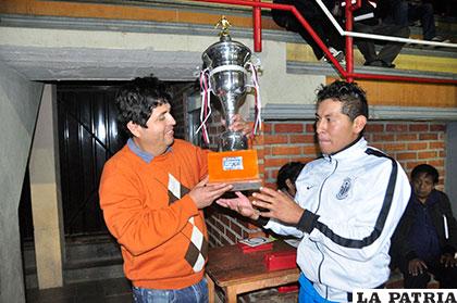 Jimmy Gonzales, capitán del equipo de Cochabamba, recibe el trofeo de campeón de parte de Juan Carlos Alarcón