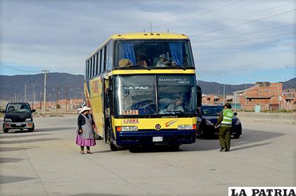 Un bus recoge pasajeros en la vía pública y el conductor es reprendido por una policía