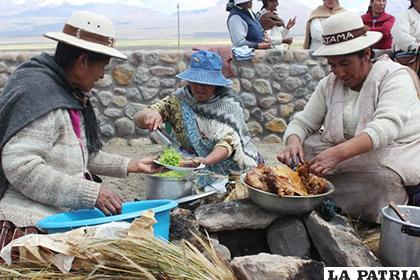 Mujeres de la comunidad Sajama mientras preparan un plato de comida que se cocina debajo de la tierra /yimg.com
