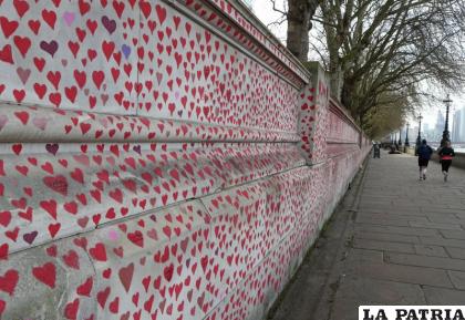 Dos personas corren junto a un muro convertido en lugar de recuerdo a las víctimas del Covid-19, en la orilla sur del Támesis ante el Hospital de Santo Tomás y enfrente del Parlamento, en Londres /AP Foto/Tony Hicks