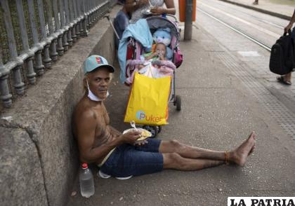 Un hombre come el almuerzo donado por la Fundación Leao XIII durante la pandemia de Covid-19, en Río de Janeiro /AP Foto/Silvia Izquierdo