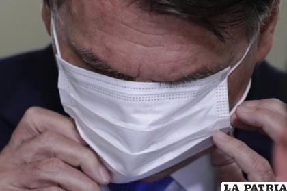 El presidente brasileño Jair Bolsonaro se ajusta su mascarilla durante una conferencia de prensa /AP Foto/Eraldo Peres