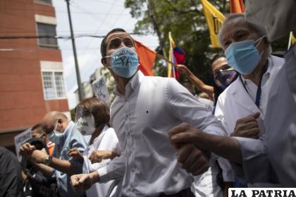 El líder opositor venezolano Juan Guaidó, usa mascarilla al sumarse a una marcha de representantes de trabajadores sanitarios por las calles de la capital venezolana para exigir el ingreso masivo de vacunas contra el Covid-19 /AP Foto/Ariana Cubillos