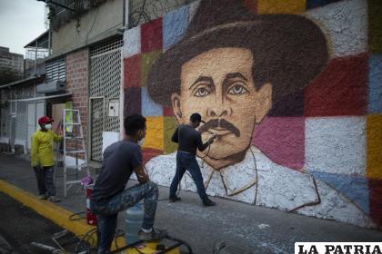 El artista venezolano Miguel García da los últimos toques a su mural con la imagen del doctor José Gregorio Hernández, en Caracas /AP Foto/Ariana Cubillos