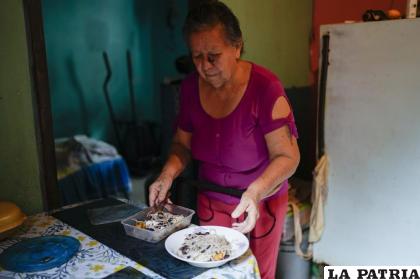 Maybel Sequera reparte un plato donado de fideos y frijoles para compartirlo con su esposo en su casa /Foto AP/Ariana Cubillos

