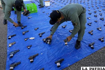 Policías recogen pistolas durante una presentación de destrucción de armas en Ciudad de Panamá 
/AP Foto /Arnulfo Franco
