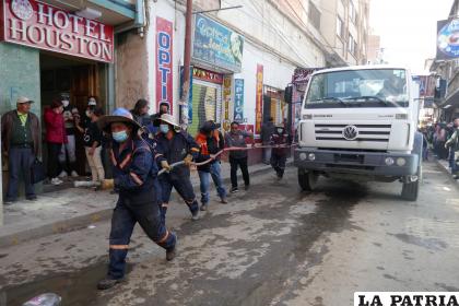 Cisterna llega al lugar y distintas personas ayudan a trasladar la manguera