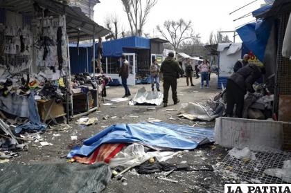Una persona muerta yace en el piso cubierta con plástico en un mercado callejero tras un ataque de artillería /AP Foto
