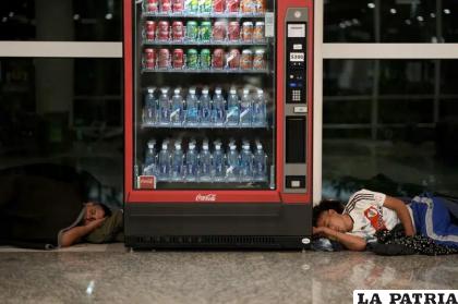 Hombres sin hogar duermen a ambos lados de una máquina de venta de bebidas en el aeropuerto internacional de Jorge Newbery /AP Photo /Natacha Pisarenko