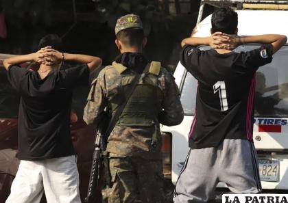 Un militar comprueba la identidad de dos jóvenes en plena calle en el barrio de La Campanera en Soyapango /AP Foto/Salvador Melendez)