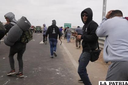 Un migrante se prepara para lanzar una piedra durante un enfrentamiento con la policía antidisturbios peruana /Foto AP/Martín Mejía
