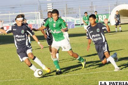 Alcides Peña, intenta penetrar entre dos defensores