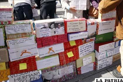 Varias personas con carteles y cajas de regalos en búsqueda de sus familiares (Foto: EFE)