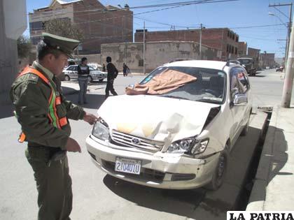 El investigador de accidentes muestra el capó del taxi