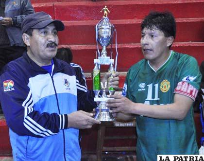 Cáceres recibe el trofeo de campeón de parte del dirigente Arellano