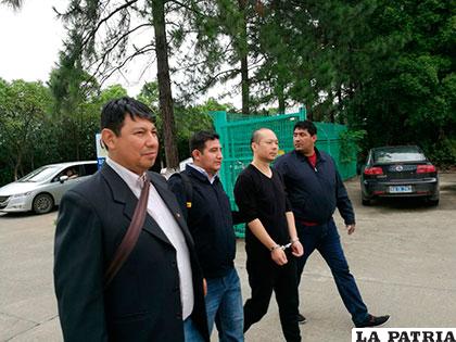 El súbdito chino esposado es trasladado por autoridades policiales