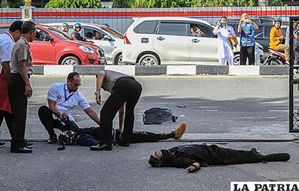 Los espectadores toman fotos mientras la policía examina los cuerpos de dos 
atacantes