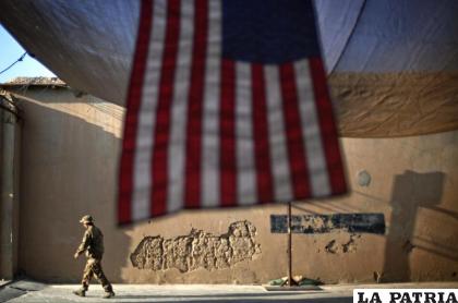 Un soldado estadounidense pasa cerca de una bandera de Estados Unidos en la provincia de Kunar, Afganistán /AP Foto/David Goldman, archivo