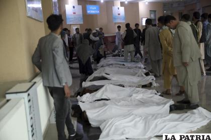 Hombres afganos intentan identificar los cuerpos en un hospital después de que explotara una bomba cerca de una escuela /AP Foto/Rahmat Gul
